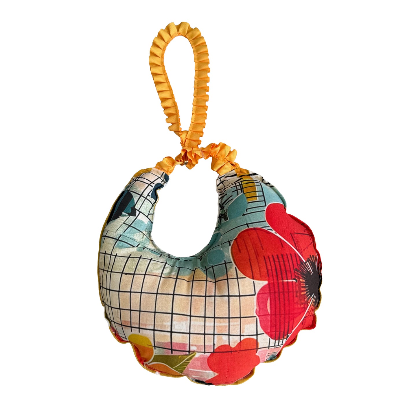 A small crescent-shaped fabric pouch with a yellow coiled handle, featuring a multicolor pattern of red flowers, green leaves, and a black grid over a light blue and beige background, isolated on a white background.